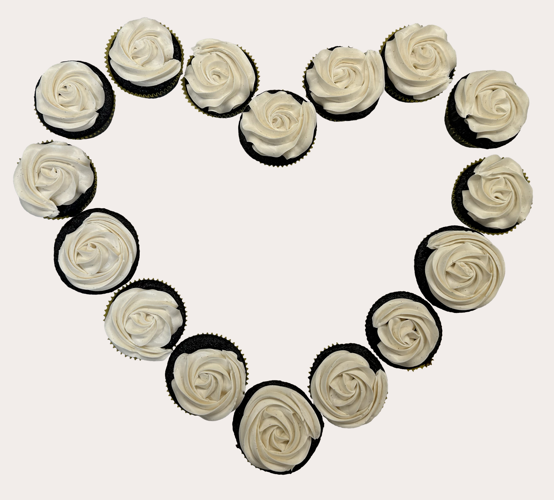 Chocolate cupcakes with white frosting creating the shape of a heart.